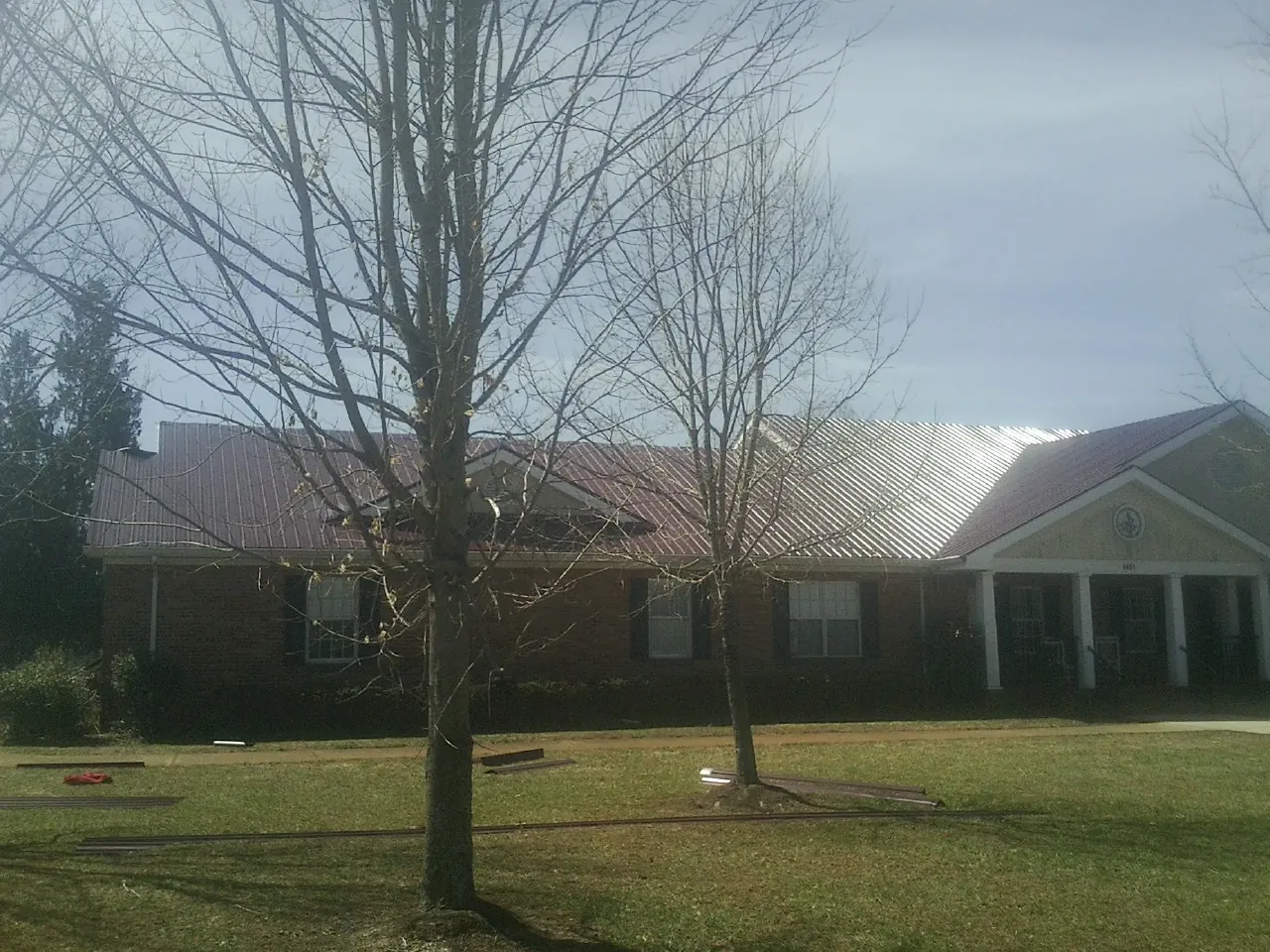 Red metal roof on a brick building seen from the front lawn in Cortez
