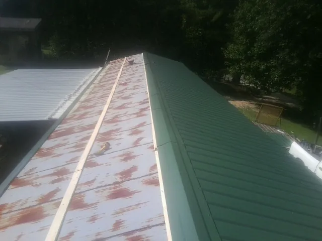 Old rusted panels beside newly installed green metal roofing — Wind Damage Roof Repair by Roofing Brothers in Cortez