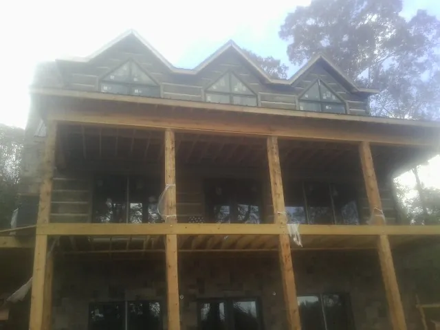 Dormers and porch framing on a large log home under construction — Roof Coating work by our crew in Cortez