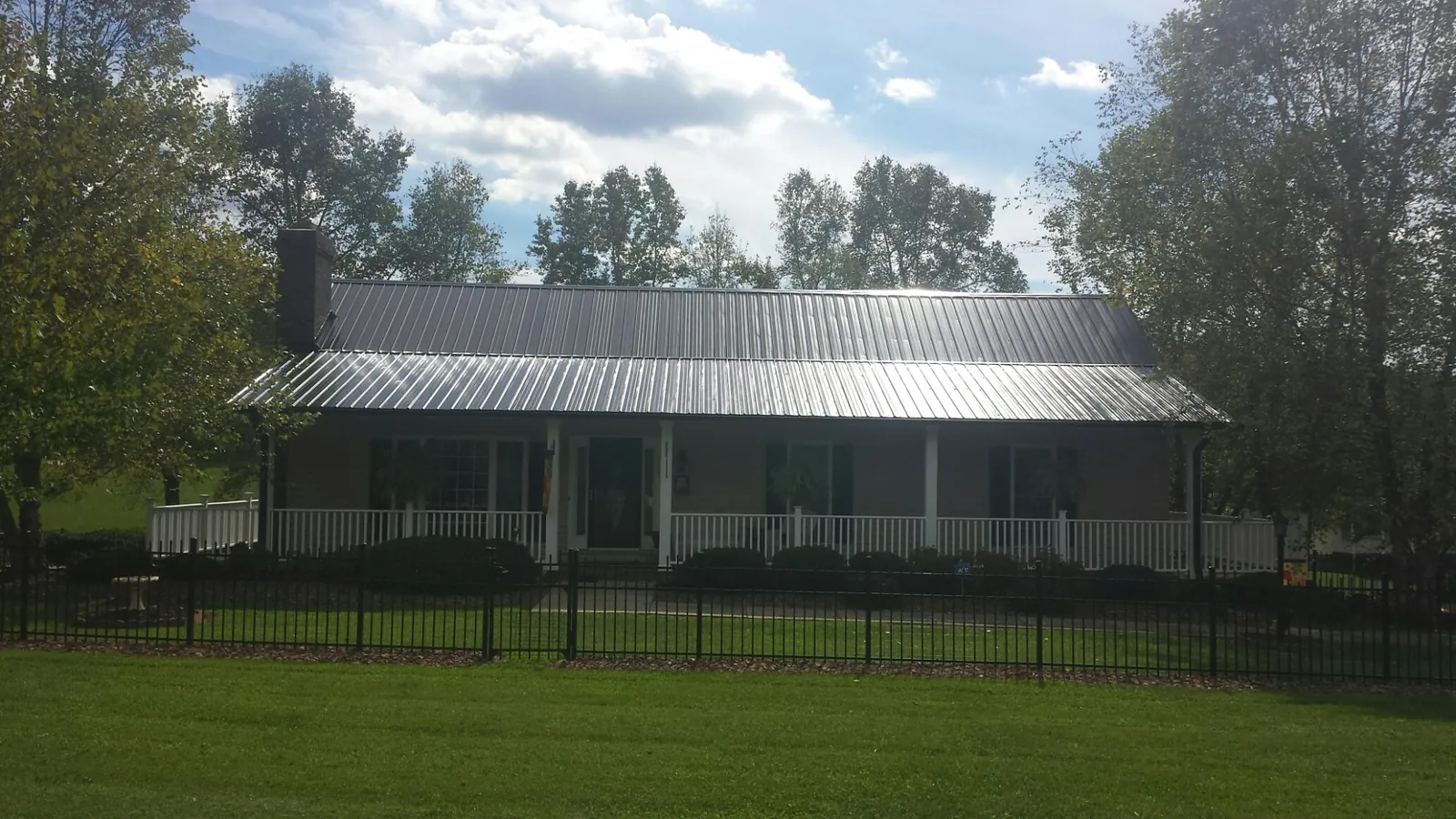 Gray metal roof on a brick ranch with a full width front porch — Gutter Guard Installation work by our crew in Cortez