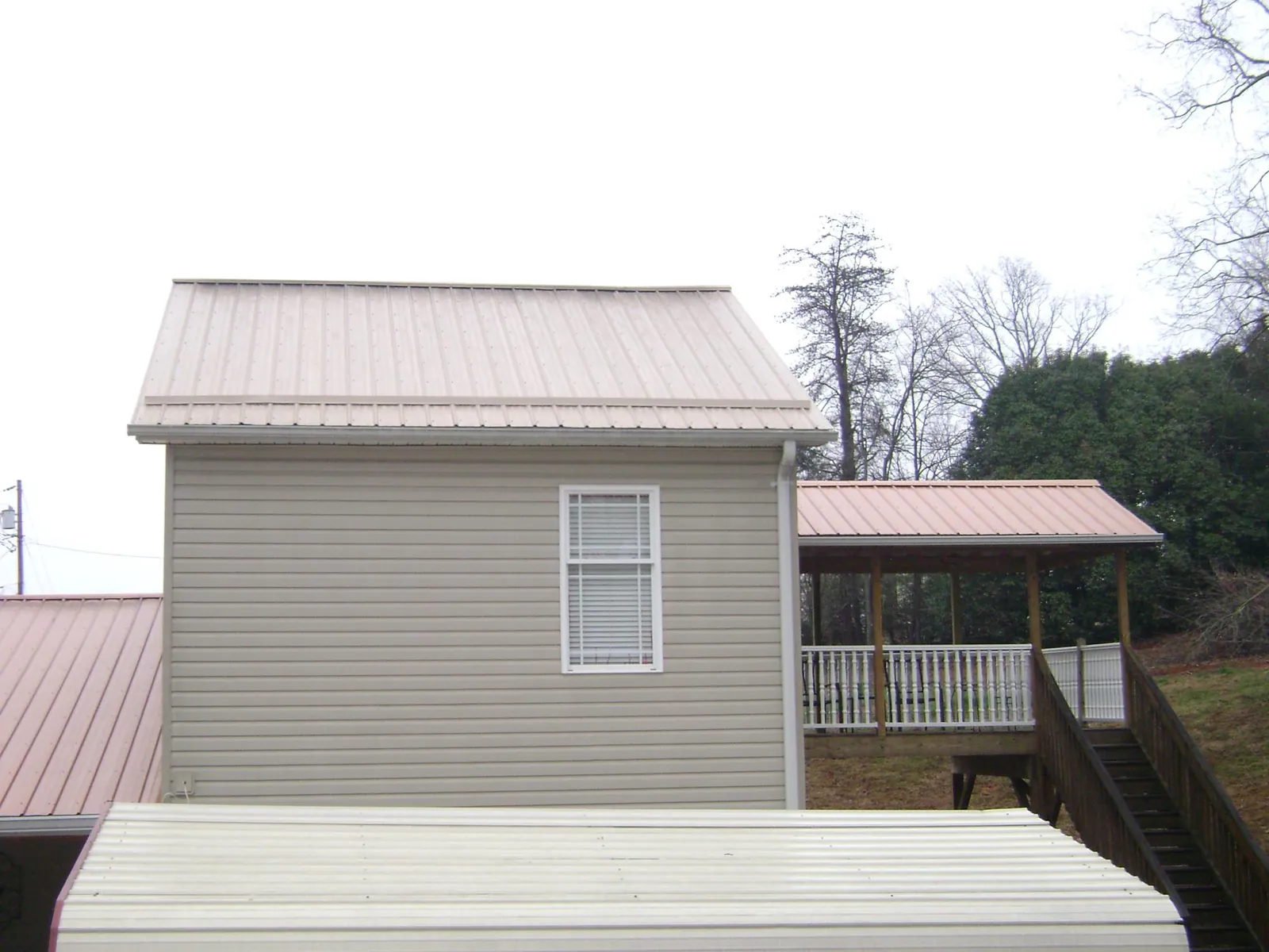 Tan metal roofs on a two story addition and attached porch, from a Roof Replacement job in Cortez
