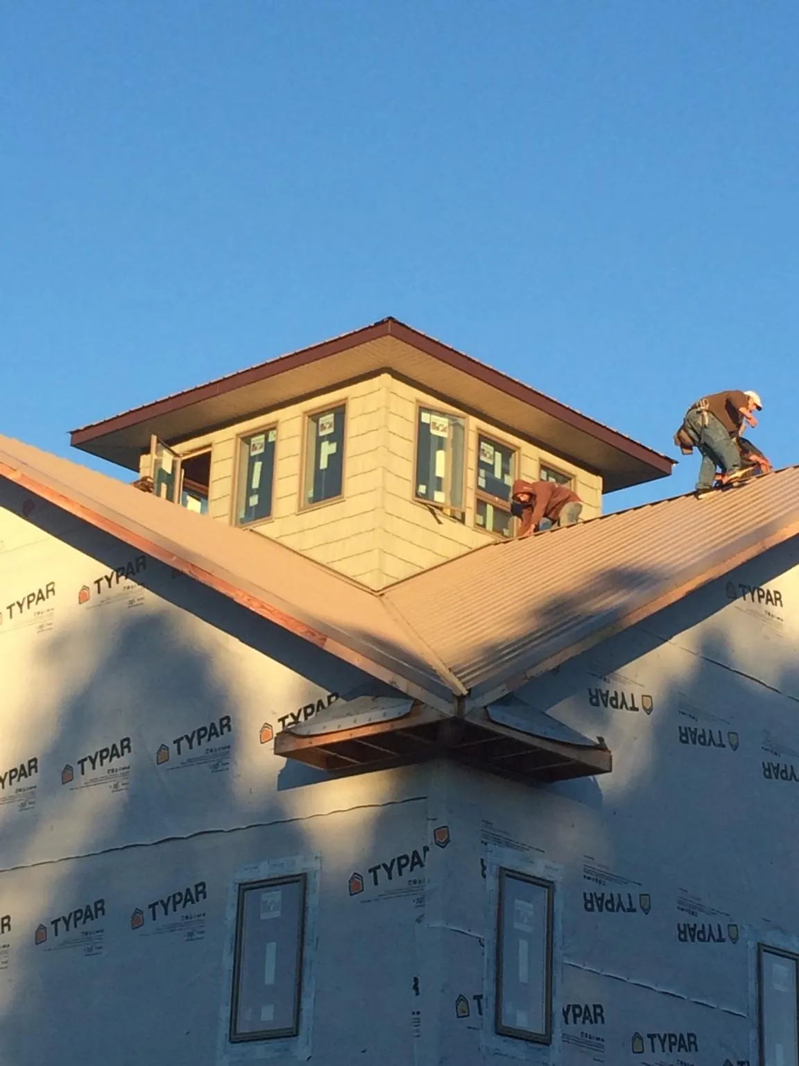 Roofers working around a rooftop cupola on a new metal roof at sunset — Roof Waterproofing in Cortez by Roofing Brothers